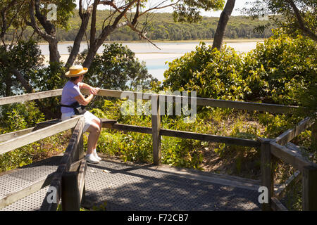 Femme assis sur un banc avec vue sur le lac d'entrée Conjola Banque D'Images