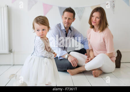 Couple avec leur jeune fille assise sur le sol en studio photographes, posant pour une photo. Banque D'Images