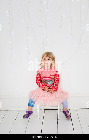 Jeune fille assise sur une chaise dans un studio de photographes, posant pour une photo. Banque D'Images