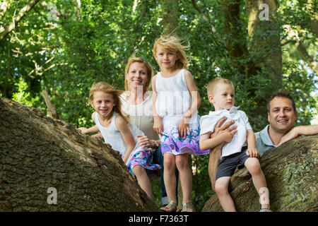 Famille avec trois enfants par un arbre dans une forêt, posant pour une photo. Banque D'Images