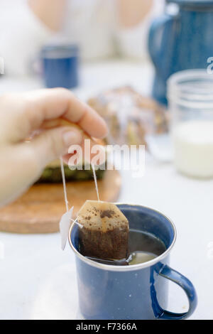 Gros plan d'une part, la suppression d'un sachet d'une tasse de thé. Banque D'Images