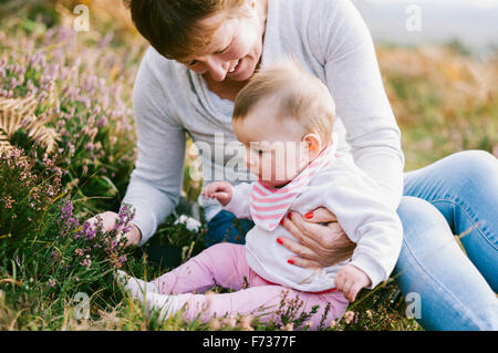 Une femme assise sur le sol tenant une jeune fille de bébé. Banque D'Images