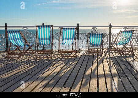 Une rangée de chaises longues vides en bois sur Brighton Pier, East Sussex Angleterre Royaume-Uni Banque D'Images