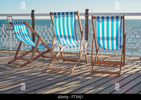 Une rangée de chaises longues vides en bois sur Brighton Pier, East Sussex Angleterre Royaume-Uni Banque D'Images