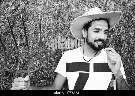 Beau cowboy tenant une fourche en stable Banque D'Images