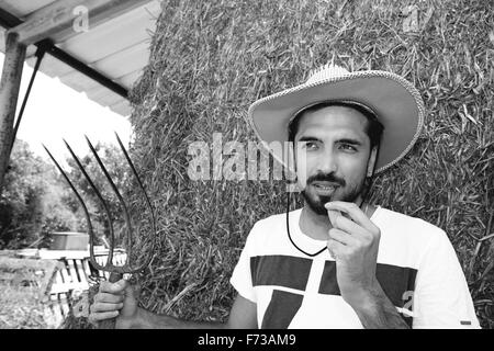 Beau cowboy tenant une fourche en stable Banque D'Images