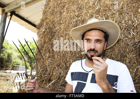 Beau cowboy tenant une fourche en stable Banque D'Images