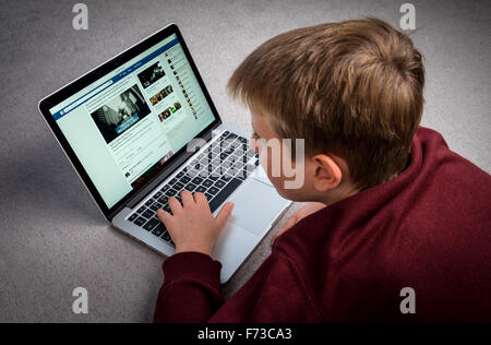 Un garçon à la recherche à Facebook sur un ordinateur portable Banque D'Images