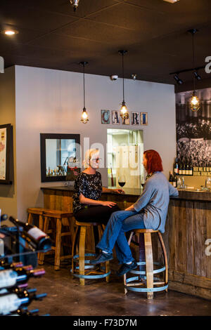 Deux femmes s'asseoir au bar d'une salle de dégustation de vins et de tous les vins unique bénéficie sur le nord-ouest. Banque D'Images