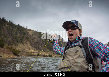 Un jeune pêcheur femelle réagit à l'absence d'un poisson tout en piège à ours pêche Canyon sur Montana's Madison River. Banque D'Images