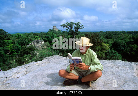 Visiteur au sommet de la pyramide principale se détend, le parc national de Tikal, Guatemala. Banque D'Images