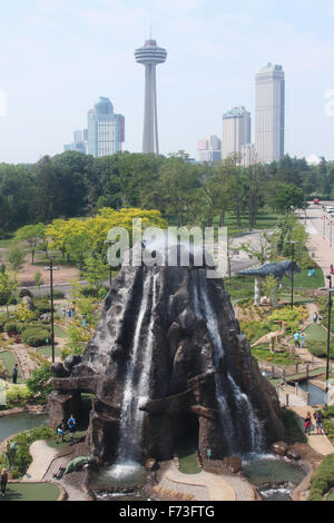 Volcan dans le parc de dinosaures le golf miniature, Dinosaur Adventure Golf. La tour Skylon et bâtiments de l'hôtel Fallsview en arrière-plan. Banque D'Images