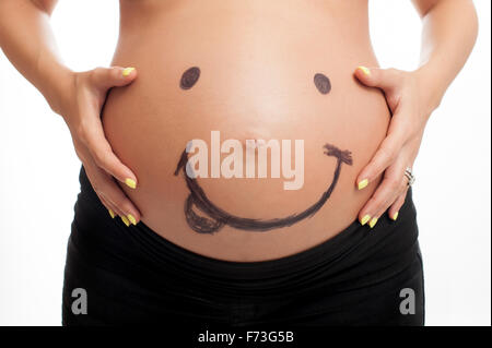 Un smiley dessiné sur un ventre de femme enceinte. Banque D'Images