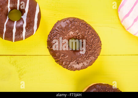 Beignes au chocolat sur fond de bois jaune Banque D'Images