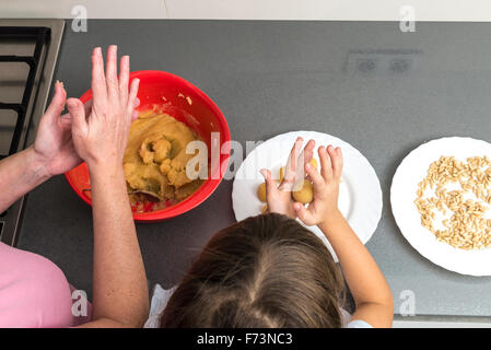 Mère et fille pour faire panellets massepain à pétrir dans la cuisine. Banque D'Images