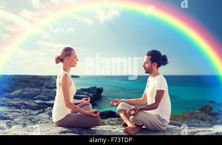 Heureux couple méditant dans lotus poser on beach Banque D'Images