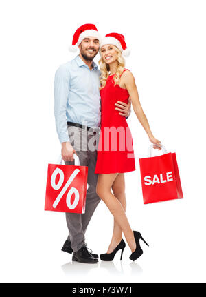 Couple heureux dans santa hats avec red shopping bags Banque D'Images