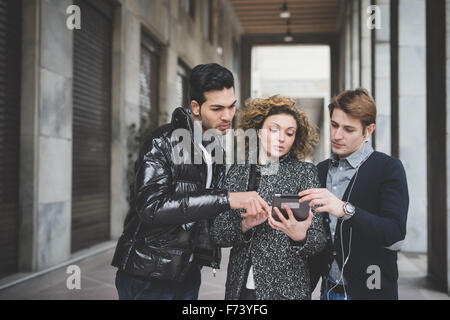 La moitié de la durée du travail des gens d'affaires multiraciale en ville en plein air à l'aide d'un comprimé, tous à la recherche vers le bas et en appuyant sur le Banque D'Images