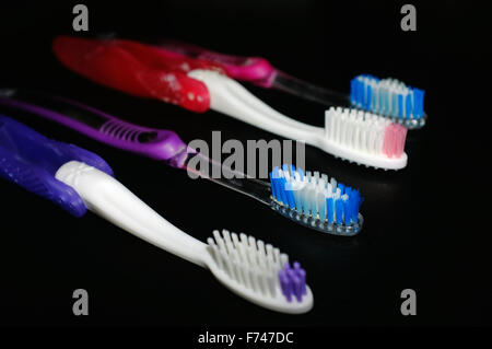 Une rangée de quatre têtes de brosse à dents photographié sur un fond noir. Banque D'Images