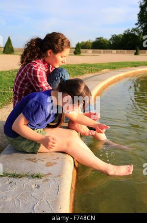 Les jeunes filles à jouer avec la fontaine Banque D'Images