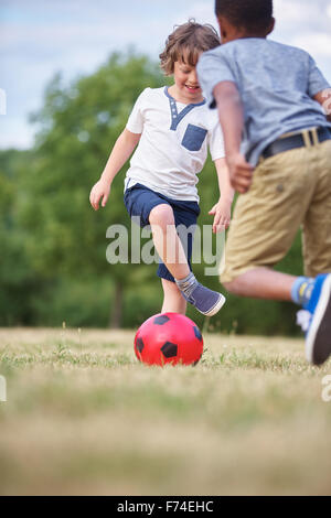 Deux enfants heureux à jouer au soccer au parc Banque D'Images