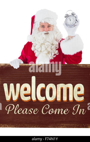 Image composite de santa claus holding réveil et signer Banque D'Images