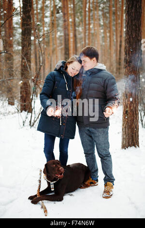 Heureux Couple avec chien labrador retriever soir profiter de l'hiver avec des cierges de fête pour Noël Temps Banque D'Images