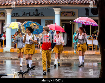 Les écoliers, les étudiants à traverser une rue, pluie de Vinales, parapluies, manger de la crème glacée, Viñales, Cuba, Pinar del Rio, Cuba, Street Banque D'Images