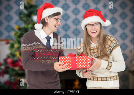 Image composite de hipster geek couple holding present Banque D'Images