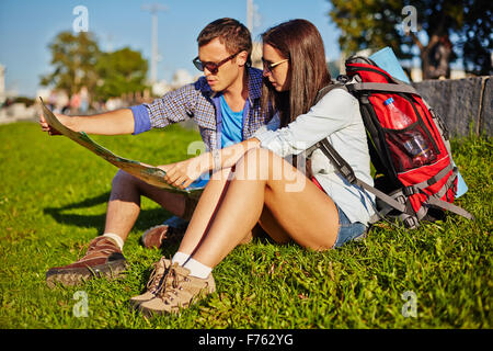 Jeune couple de l'emplacement sur l'herbe et de l'examen de la carte
