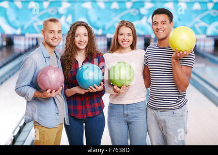 Groupe de quatre amis holding Bowling Balls and smiling Banque D'Images