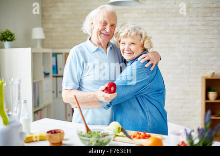 Happy mari et femme en embrasser looking at camera dans la cuisine Banque D'Images