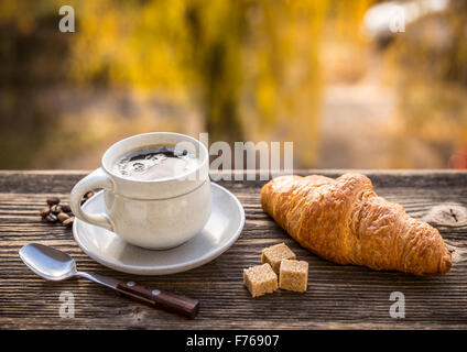 Café et croissant, sur fond de soleil d'automne floue Banque D'Images