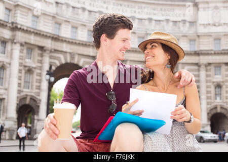 Jeune couple assis ensemble dans la rue Banque D'Images