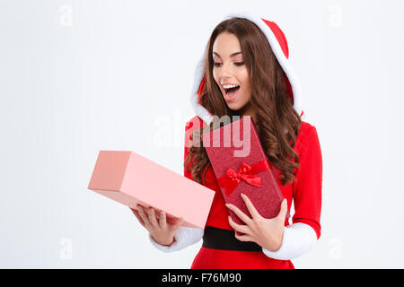 Contenu heureux surpris jeune femelle bouclés en costume père noël rouge avec capuche à l'intérieur de présenter fort sur fond blanc Banque D'Images