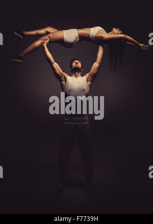 Athletic couple doing yoga acro, studio shot Banque D'Images