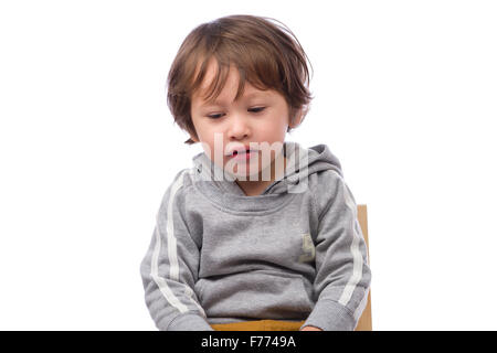 Un mignon petit garçon de 3 ans avec une expression triste sur un fond blanc. Banque D'Images