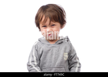 Un mignon petit garçon de 3 ans avec une expression de colère sur un fond blanc. Banque D'Images