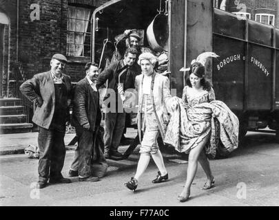 Un couple de jeunes gens masqués passent devant un groupe de travailleurs,Londres,ANGLETERRE,uk. 1967 Banque D'Images