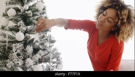 Jolie jeune femme africaine décorant un arbre de Noël Banque D'Images