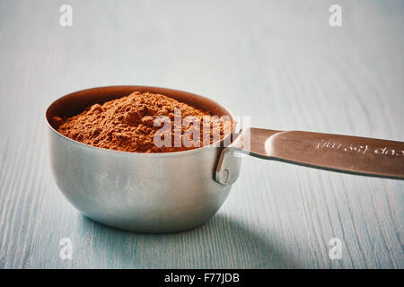 Mesure graduée cuillère cacao sur table en bois bleu Banque D'Images