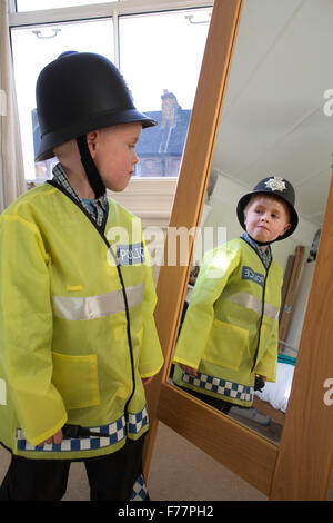 (Garçon, 4 ans) portant son British 'Bobby' costume Agent de police devant le miroir à la maison dans sa maison de Londres, UK Banque D'Images