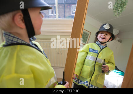 (Garçon, 4 ans) portant son British 'Bobby' costume Agent de police devant le miroir à la maison dans sa maison de Londres, UK Banque D'Images