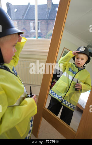 (Garçon, 4 ans) portant son British 'Bobby' costume Agent de police devant le miroir à la maison dans sa maison de Londres, UK Banque D'Images