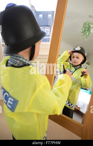 (Garçon, 4 ans) portant son British 'Bobby' costume Agent de police devant le miroir à la maison dans sa maison de Londres, UK Banque D'Images