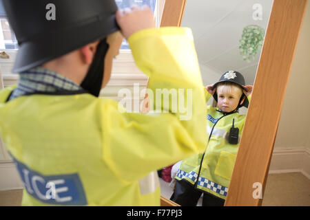 (Garçon, 4 ans) portant son British 'Bobby' costume Agent de police devant le miroir à la maison dans sa maison de Londres, UK Banque D'Images