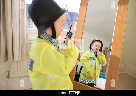 (Garçon, 4 ans) portant son British 'Bobby' costume Agent de police devant le miroir à la maison dans sa maison de Londres, UK Banque D'Images