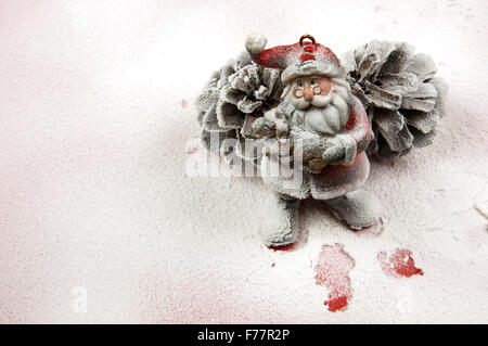 Décoration de Noël,Santa Claus figurine basée sur deux grands cônes de l'épinette sur la neige-couvert, surface rouge et à la suite de l'al. Banque D'Images