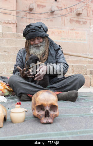 Bum bum noire Baba, un Sadhu saint siège avec son chiot et du crâne le long du Gange à Varanasi. Banque D'Images