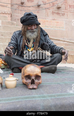 Bum bum noire Baba, un Sadhu saint siège avec son chiot et du crâne le long du Gange à Varanasi. Banque D'Images